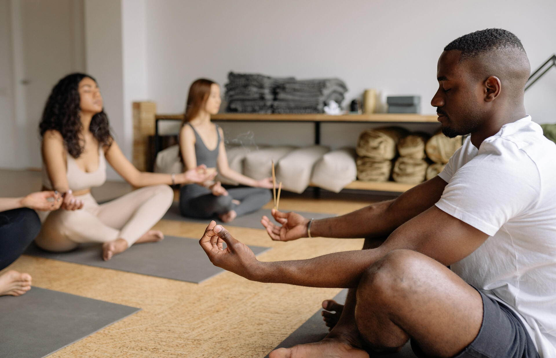 Man meditating in front of a class of women meditating