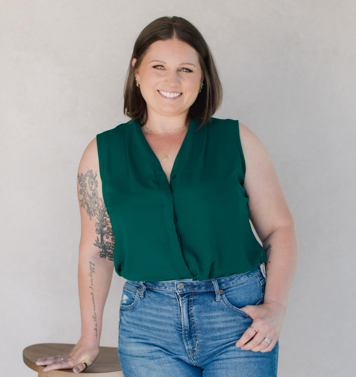 Woman with short brown hair and a green sleeveless shirt smiling